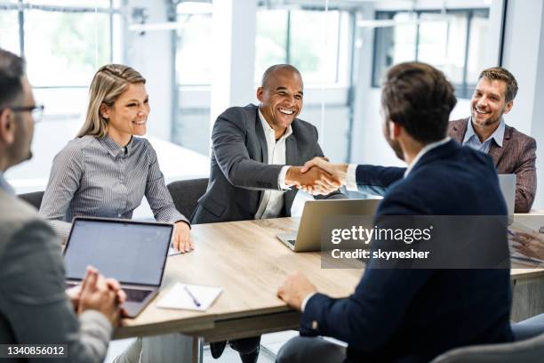 happy businessmen shaking hands on a meeting in the office. - mergers and acquisitions stock pictures, royalty-free photos & images