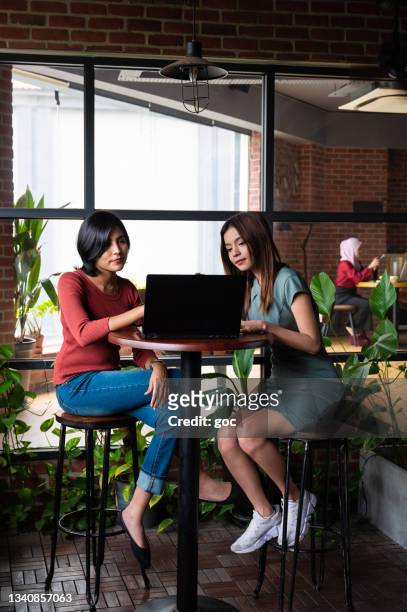 two female colleagues having work discussion at office lounge - employee wellbeing stock pictures, royalty-free photos & images