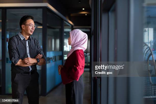 business partners having discussion at office corridor - religion diversity stock pictures, royalty-free photos & images