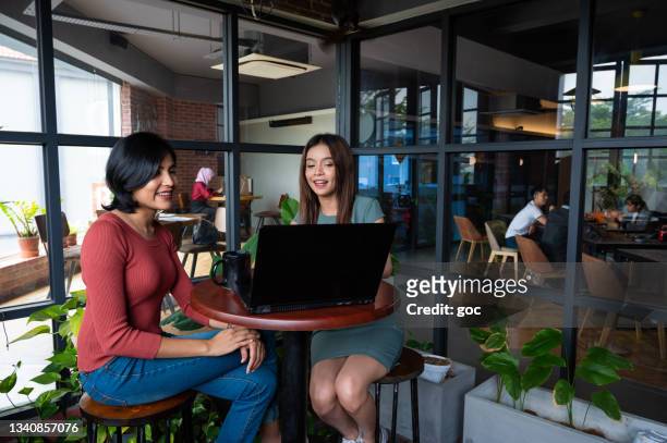 zwei geschäftspartnerinnen arbeiten gemeinsam am laptop in der bürolounge - indian lunch stock-fotos und bilder