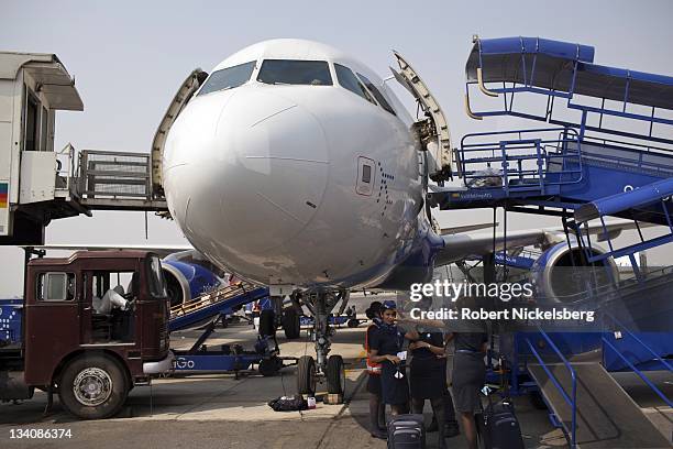 Standing below an Airbus 320, Indian crew and staff for Indigo Airlines wait to board their flight October 11, 2011 at the domestic side of the...
