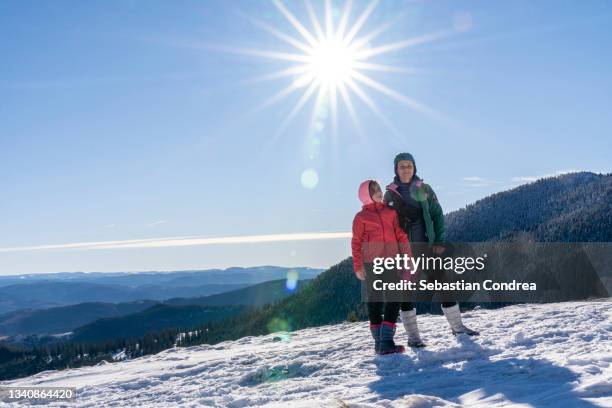 mother and her daughter are hiking in the mountains in the winter. - alps romania stock pictures, royalty-free photos & images