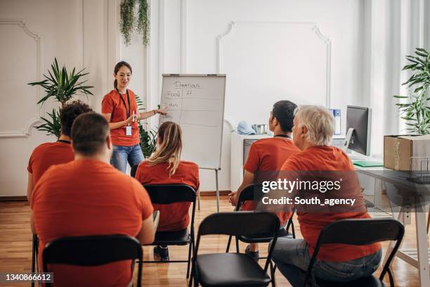 team of volunteers having a meeting about plans and target for donations - non profit organization stock pictures, royalty-free photos & images