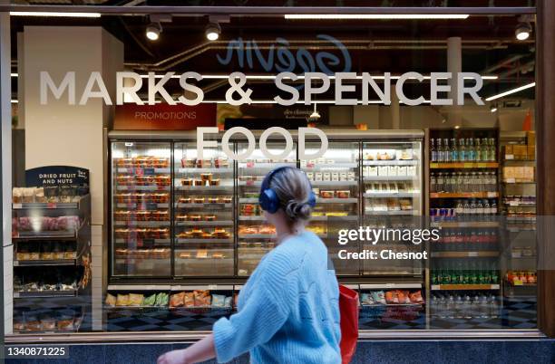 Customer wearing a protective face mask walk past shelves inside a Marks & Spencer food store on September 17, 2021 in Paris, France. The British...