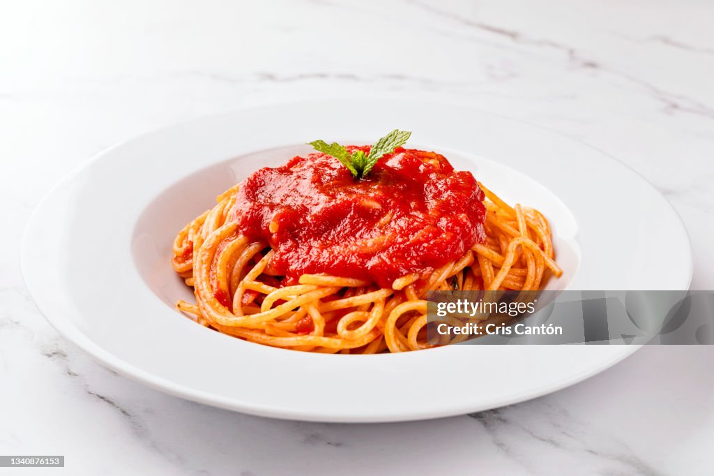 Spaghetti with tomato sauce on white background.