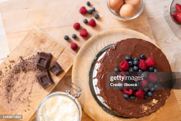 woman baking at home: chocolate sponge cake with berries - making cake stockfoto's en -beelden