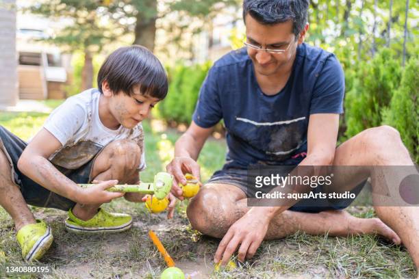 father and child play i̇n mud with toys i̇n backyard , dirty and happy - happy dirty child stockfoto's en -beelden
