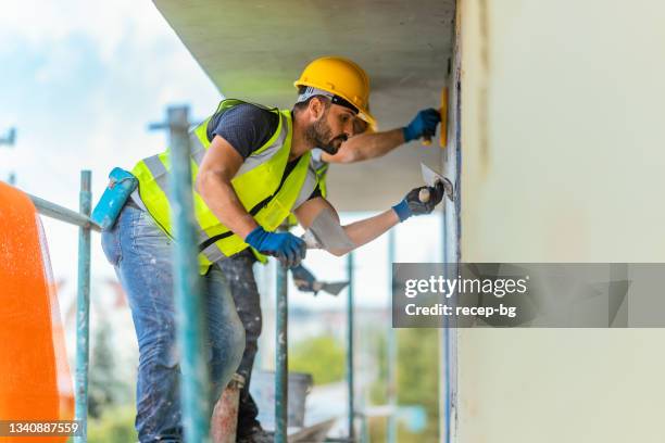 construction workers applying plaster on building facade - trabalhador manual imagens e fotografias de stock
