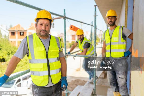 portrait of construction workers at the construction site - applying plaster stock pictures, royalty-free photos & images