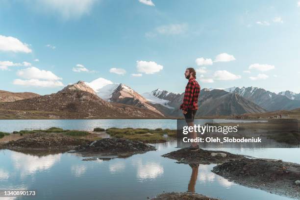 scenic view of man near the lake in tien shan mountains in kyrgyzstan in summer - lake issyk kul stock pictures, royalty-free photos & images