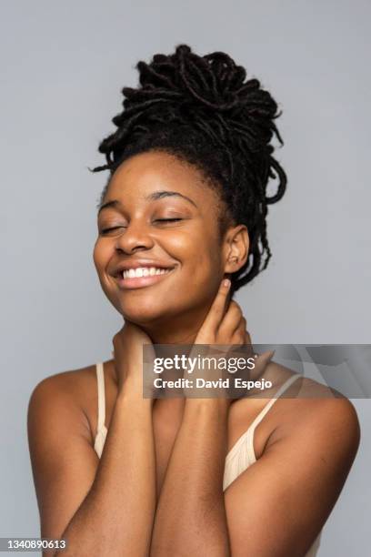 cheerful black model massaging neck on gray background - cutis claro fotografías e imágenes de stock