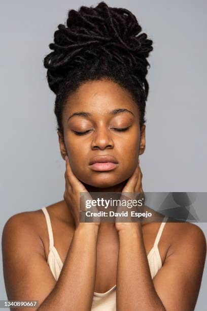 black model massaging neck on gray background - pain face portrait stockfoto's en -beelden