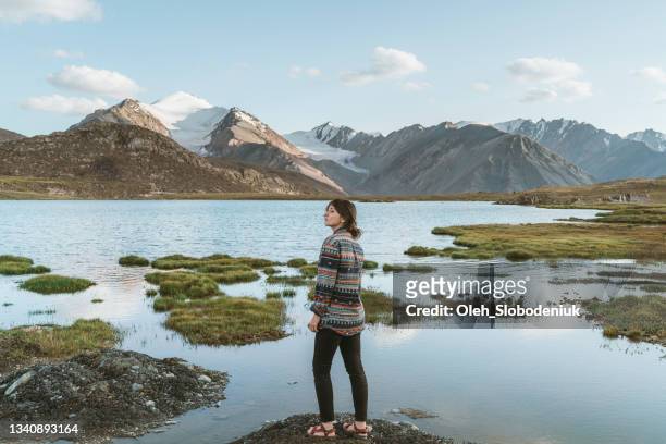 woman near the lake in tien shan mountains in kyrgyzstan in summer - kyrgyzstan stock pictures, royalty-free photos & images