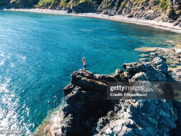 vista aerea di un uomo in piedi su una roccia nel mare - livorno foto e immagini stock