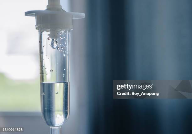 close up of an intravenous fluids given water, sugar and salt to patient who can't eat or drink normally. - infuus stockfoto's en -beelden