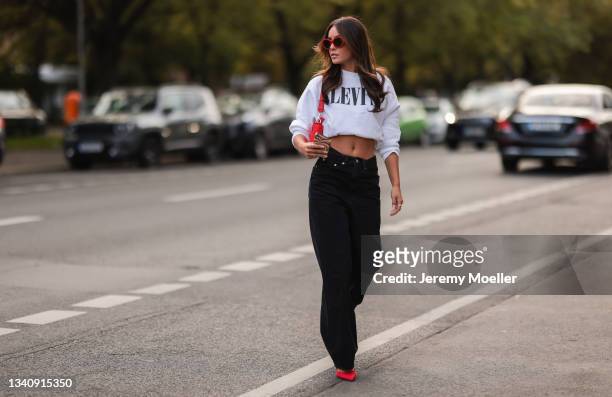 Lara Runarsson wearing red shades, a white levis pullover, black jeans and red heels on September 13, 2021 in Berlin, Germany.