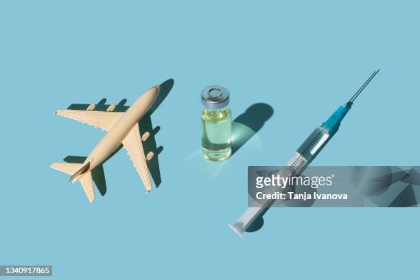 vials, syringes with a vaccine and airplane on a blue background. concept covid-19 vaccine immunization and travel to the pandemic. - vacances plage stock-fotos und bilder