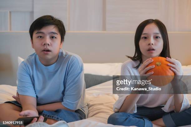 asian siblings binge watching scary halloween movies - binge tv stockfoto's en -beelden