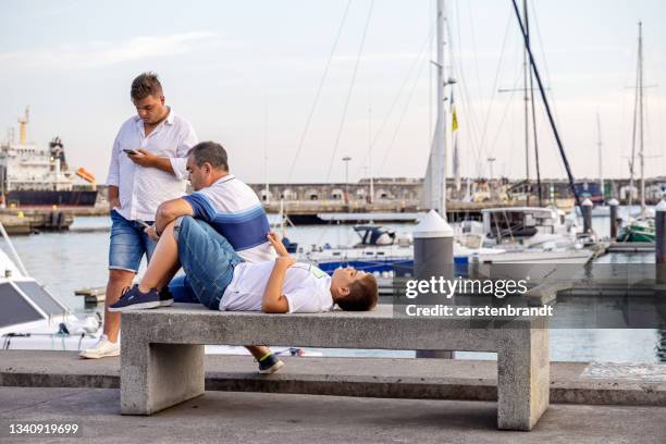 three young men at a harbor promenade - ponta delgada stock pictures, royalty-free photos & images