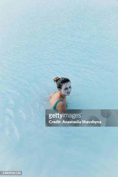 young woman enjoying a day in thermal spa pool with turquoise water in iceland - mud therapy stock pictures, royalty-free photos & images