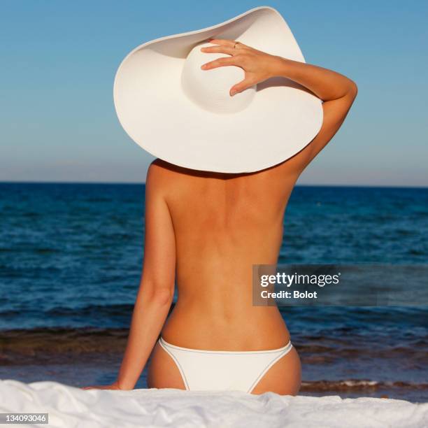 jovem mulher com chapéu de sol branco relaxante na praia - tronco nu imagens e fotografias de stock