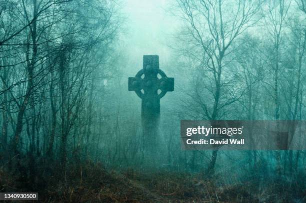 a spooky graveyard with a cross silhouetted in a forest. with a grunge, vintage edit. - 墓地 ストックフォトと画像