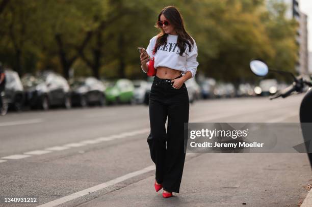 Lara Runarsson wearing red shades, a white levis pullover, black jeans and red heels on September 13, 2021 in Berlin, Germany.