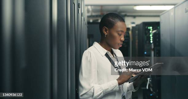 scatto di una giovane donna che utilizza un tablet digitale mentre lavora in un data center - server room women foto e immagini stock