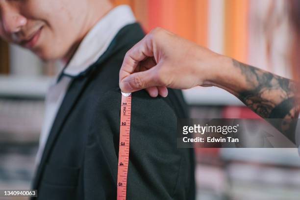 close up asian chinese senior man tailor measuring his client's body size for new blazer making at studio - bespoke stock pictures, royalty-free photos & images