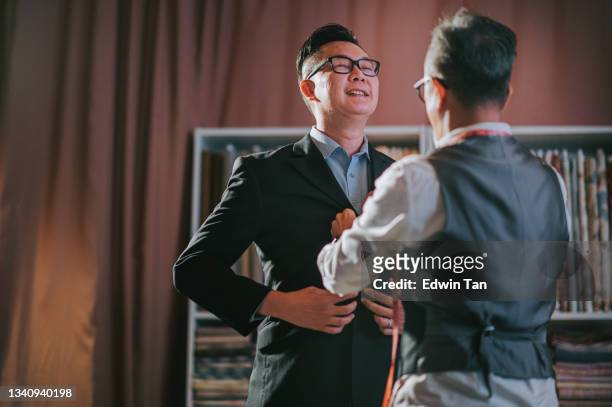 asian chinese senior man tailor helping his client trying on new tailored blazer suit at his studio - shopping asia stock pictures, royalty-free photos & images