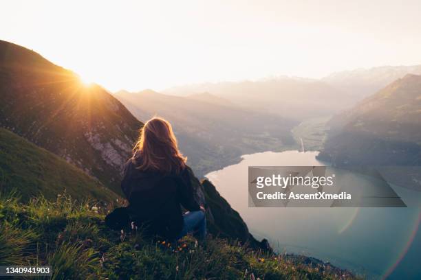 la excursionista femenina se relaja en la cresta de la montaña al amanecer - mujer de espaldas en paisaje fotografías e imágenes de stock