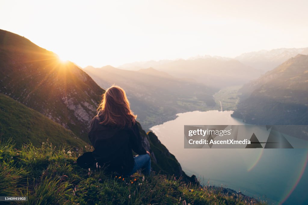 Female hiker relaxes on mountain ridge at sunrise
