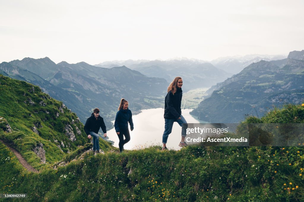 Freunde wandern bei Sonnenaufgang den grasbewachsenen Bergrücken hinauf
