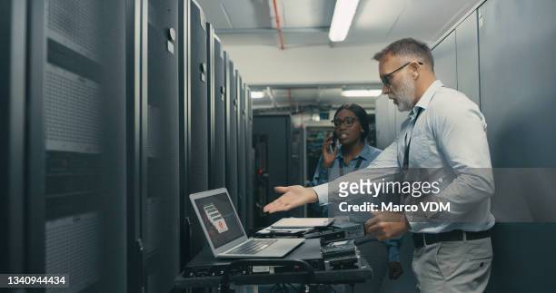 shot of a man and woman looking stressed while working in a data centre - broken laptop stockfoto's en -beelden