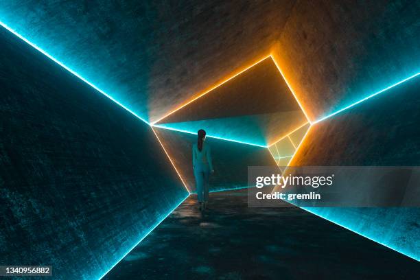 businesswoman walking in futuristic illuminated dark corridor - brutalism stock pictures, royalty-free photos & images