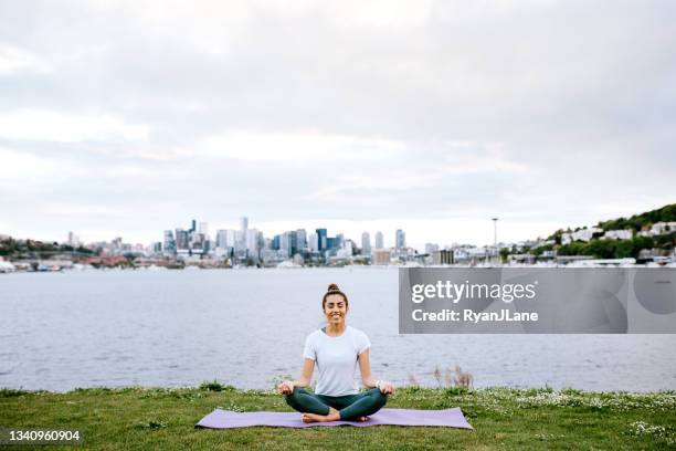 woman stretching and meditating by seattle waterfront - seattle city life stock pictures, royalty-free photos & images