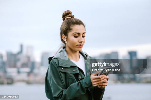 woman using wireless technology in city setting - parka stock pictures, royalty-free photos & images