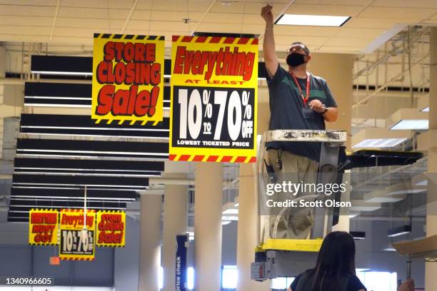 Worker hangs signs inside a Sears store at the Woodfield Mall announcing the store would be closing on September 17, 2021 in Schaumburg, Illinois....