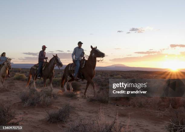 native american navajo teenagers and children riding horses together in monument valley arizona, utah at dusk under a dramatic sunset in the late summer on the tribal park - horseback riding arizona stock pictures, royalty-free photos & images