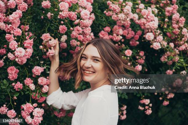 happy young woman spending summer day in garden of pink roses - white rose garden stock pictures, royalty-free photos & images