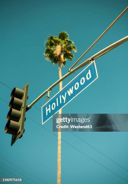 usa, california, city of los angeles, stoplight with hollywood sign hanging against clear turquoise sky - hollywood schild stock-fotos und bilder