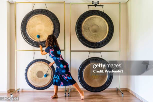 female sound therapist playing gongs with mallets in studio - music therapy stock pictures, royalty-free photos & images