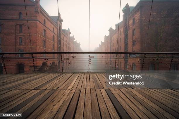 germany, hamburg, wooden bridge in historical speicherstadt district during foggy weather - hafencity hamburg stock-fotos und bilder