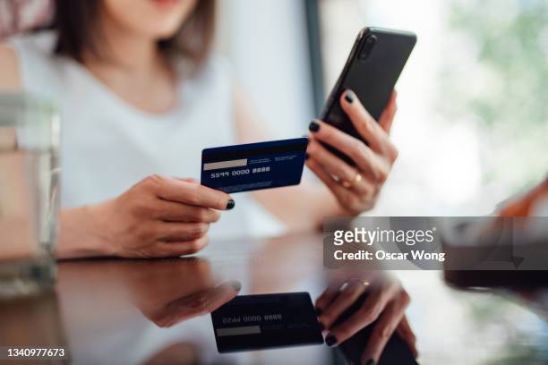 young woman managing and transferring money on smartphone - credit card stock-fotos und bilder