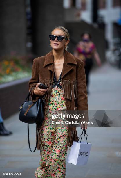Guest is seen wearing brown wild leather jacket with fringes, dress with floral print outside RIXO during London Fashion Week September 2021 on...