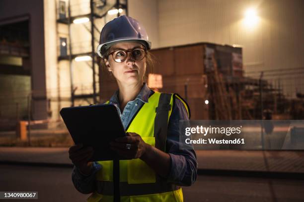 thoughtful female engineer with digital tablet standing in front of industry - hard hat ipad stock pictures, royalty-free photos & images