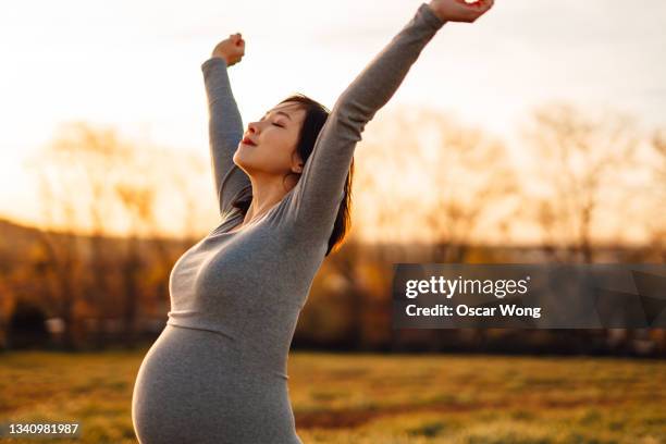 pregnant woman walking and taking fresh air in park at sunset - woman stretching sunset stockfoto's en -beelden