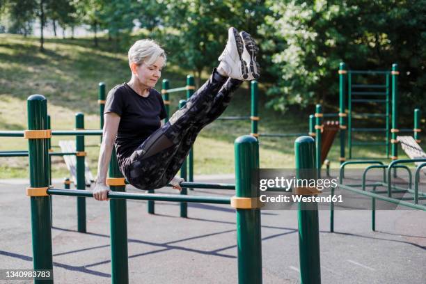 woman balancing with feet up on exercise equipment at park - adult gymnast feet stock-fotos und bilder