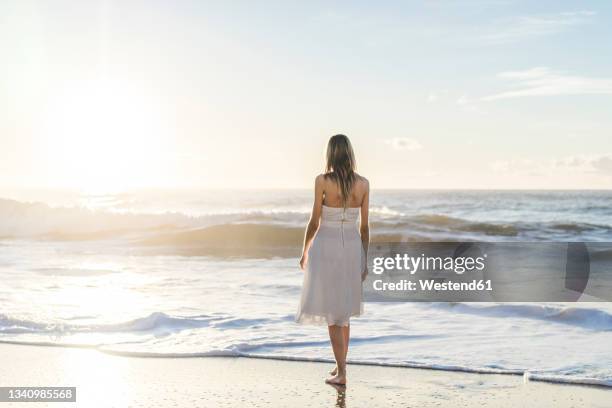 bride looking at sunrise view while standing on beach - white dress back stock pictures, royalty-free photos & images