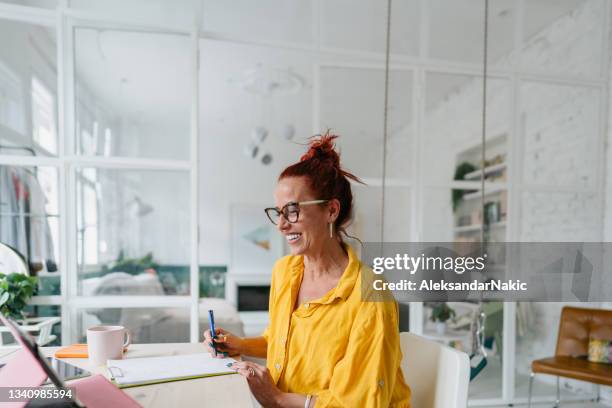 smiling mature woman working from home - older woman colored hair stock pictures, royalty-free photos & images